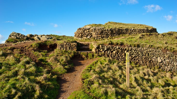 A view of the Iron Age fort with a blue sky behind at Bolt Tail, Devon